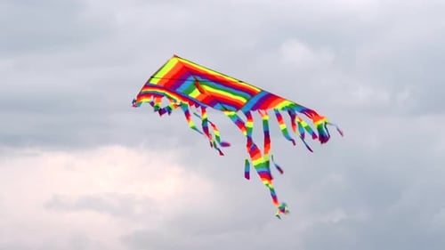 Colorful bright kite flying in the wind. Close up with kite against cloudy sky