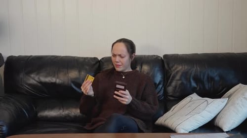 Woman Using Phone and Credit Card at Home