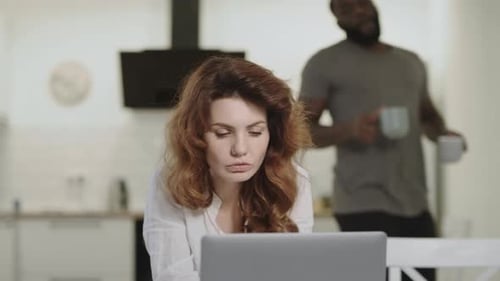 Woman Working at Computer While Man Brings Coffee