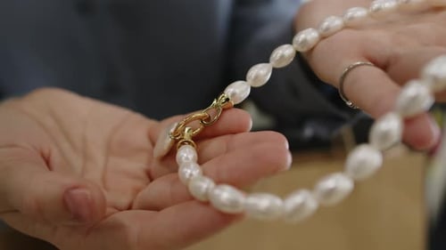 Hands of Woman Holding Dainty Pearl Necklace in Jewellery Store