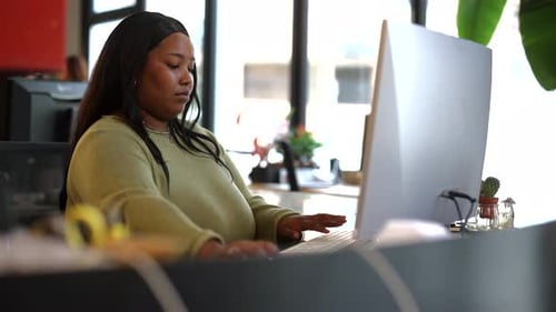 Office professional working diligently on computer, focusing intently while typing on keyboard and a