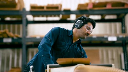 Carpenter Using a Wood Planer Machine in a Workshop