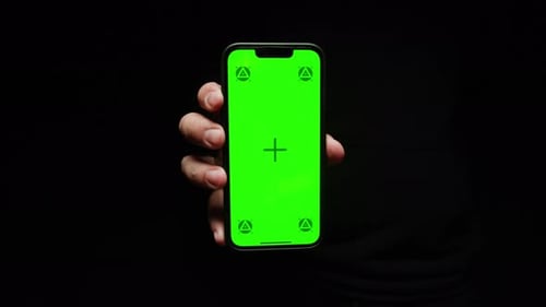 Smartphone with Chroma Key Screen on Black Background Closeup Green Screen on Mobile Phone in Hand