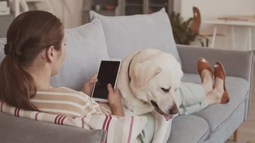 Woman Relaxing with Dog and Tablet on Couch