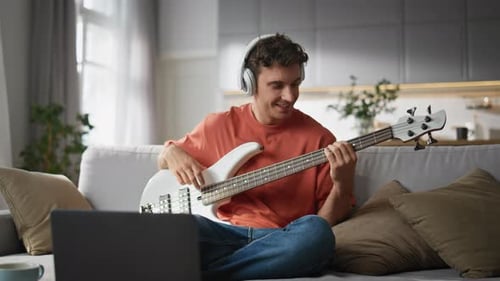 Young Man Plays Bass Guitar at Home