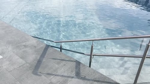 Freibad mit klarem Wasser. Die Kamera schwenkt nach links und zeigt Sonnenliegen