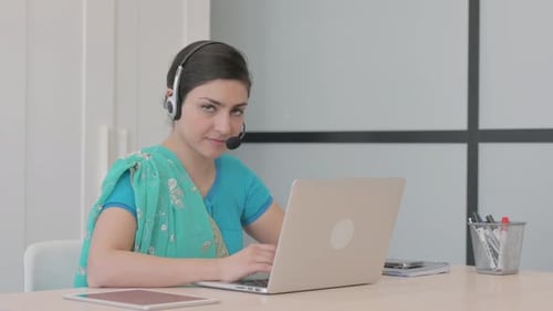 Young Indian Woman with Headset Looking toward Camera in Call Center