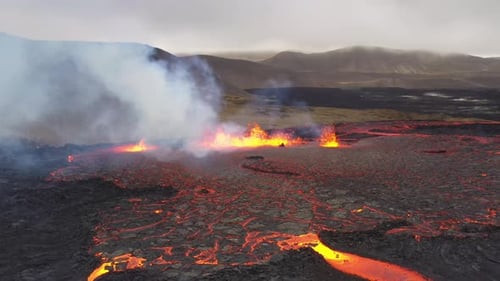 Erupção de ventilação de vulcão com rio de lava ejetado fluindo por um vale na Islândia