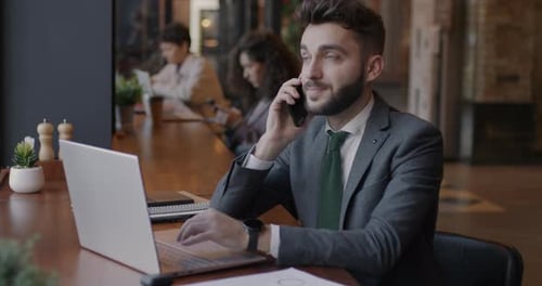 Young Adult Working on Laptop and Talking on Phone