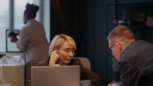 Homme et femme communiquant au bureau pendant que le photographe travaille en arrière-plan