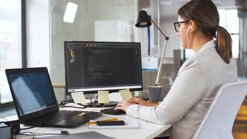 Geschäfts-, Programmier- und Technologiekonzept - Programmiererin mit Kopfhörern arbeitet mit