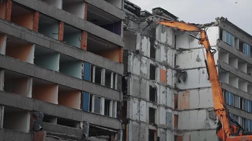 La
garra de una excavadora está arrancando el gran bloque del edificio en ruinas.