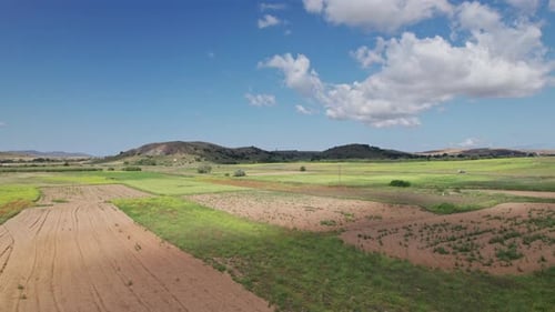 Drone s'élève au-dessus d'un vaste paysage agricole avec des parcelles sablonneuses et des champs herbeux