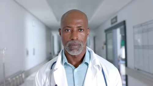 Portrait of african american male doctor wearing lab coat and stethoscope at hospital, slow motion