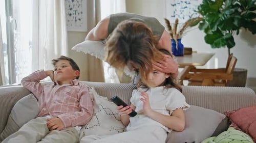 Caring Mother Kissing Kids at Cozy Couch Closeup Two Small Children Watching Tv