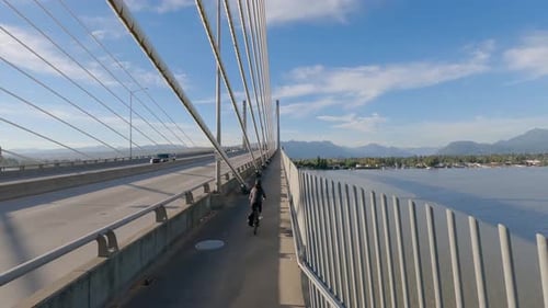 Woman Bike Riding on a Bicycle Path Over Golden Ears Bridge Over the Fraser River