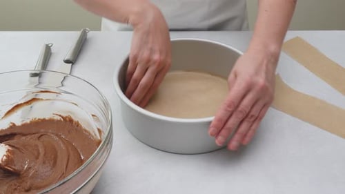Cake pan lined with parchment paper close up on kitchen table. Chocolate cake step by step recipe