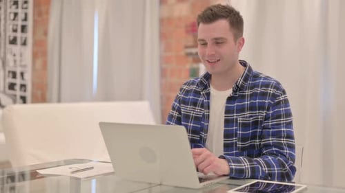 Young Adult Using Laptop for Video Call at Home