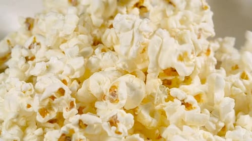 Falling Salted Popcorn into a Ceramic Bowl. Shot with High Speed Camera. Slow Motion Tossing Snack