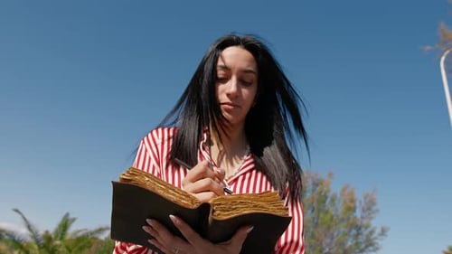Woman Writing On A Book With A Pencil