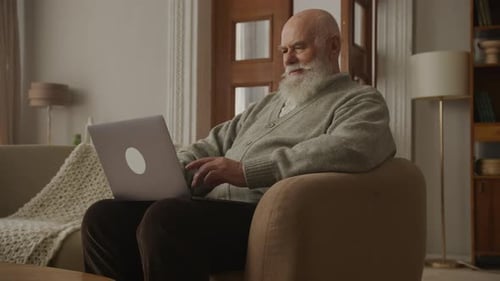 Senior Man Types on Laptop in Bright Living Room