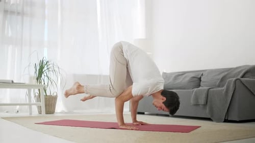 Young Man Balancing in Crow Yoga Pose at Home