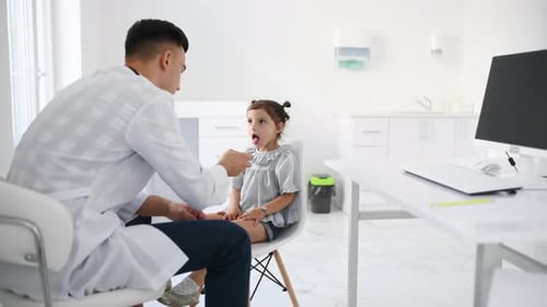 Doctor Examining Little Girl's Throat in Clinic
