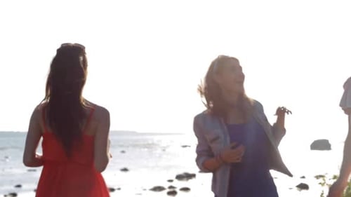 Happy women dancing on beach during sunny day