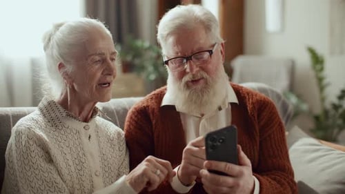 Senior Couple Using Smartphone Technology Indoors