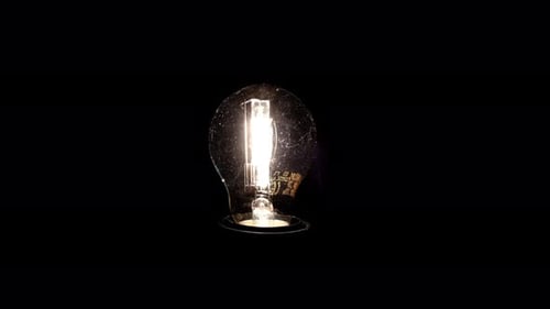 Illuminated Light Bulb Against Dark Background