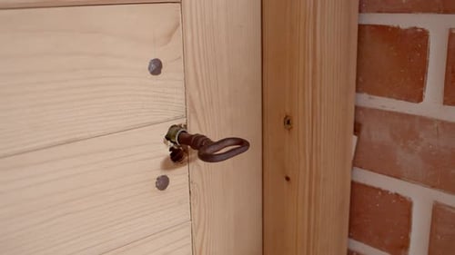 A Man In Black Sweater Opening The Metal Door Lock And Then Enters The House. Close-up