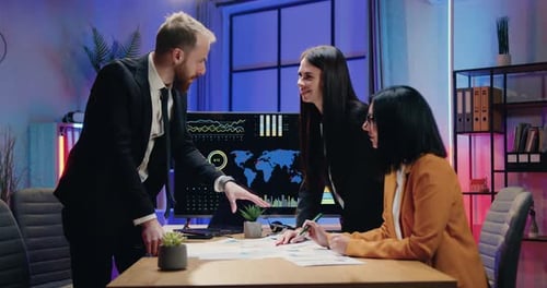 Businessman shaking hands with female colleagues during joint meeting in evening office. Business