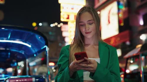 Woman Using Phone at Night in Busy City