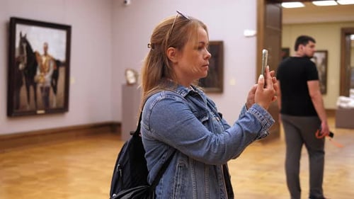 Closeup of a Young Woman Taking Pictures on Her Phone in an Art Gallery