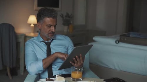 Mature Businessman with Tablet in a Hotel Room