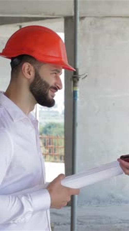 Two Builders Engaged in a Lively Discussion Over a Digital Tablet at a Construction Site