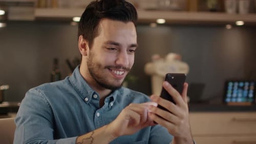 Man Smiles Using Phone in Modern Kitchen