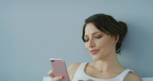 Woman Uses Mobile Phone Lying in Bed