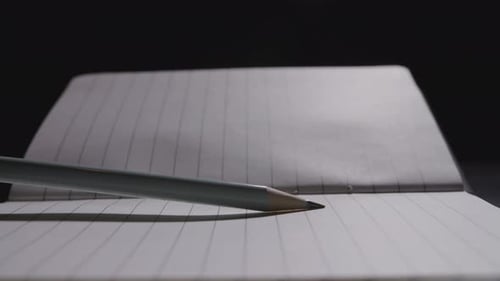 Close up of a pencil being slammed down on an open notebook