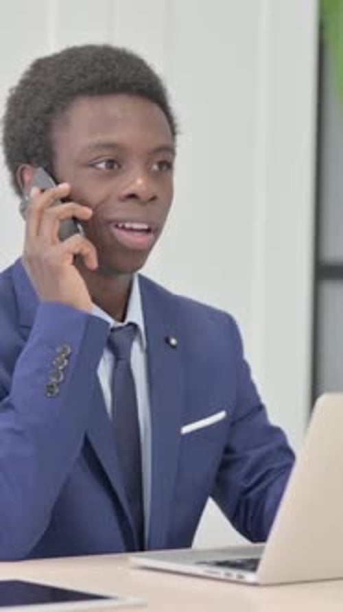 Young Professional in Suit Talking on Phone at Desk