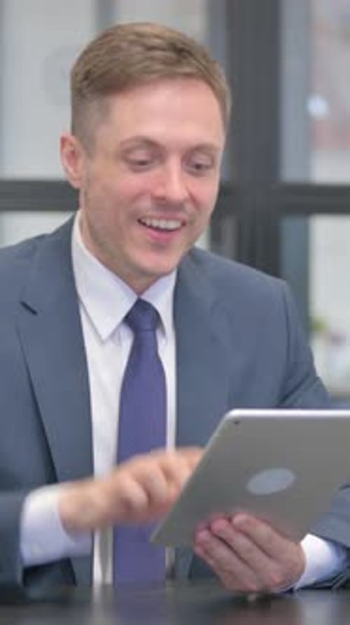 Man in Suit Works on Tablet with Positive Expression
