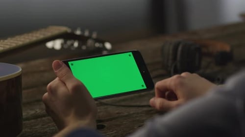 Músico usando o telefone no modo paisagem em casa. Estilo de vida causal