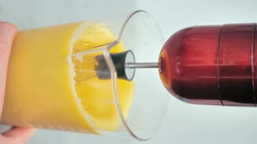 Hand Held Blender Mixing Yellow Liquid