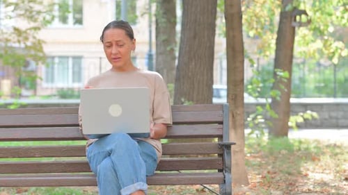 Woman Working on Laptop Outdoors in Park
