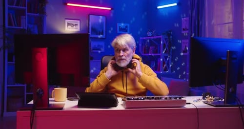 Portrait of Happy Senior Man DJ in Headphones Works on Mixer Console Creating Music on Equipment