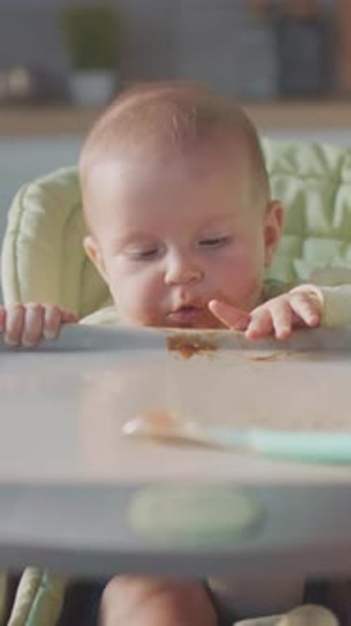 Sweet Infant in Highchair Reaches for Food