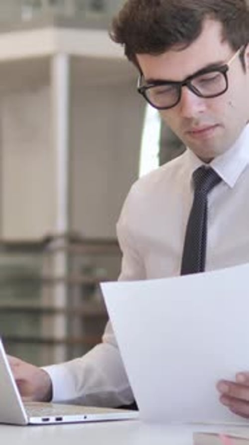 Geschäftsmann liest Dokumente im Büro, vertikales Video