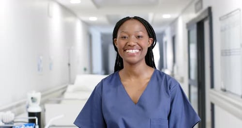 Portrait of happy african american female doctor wearing scrubs in hospital, slow motion