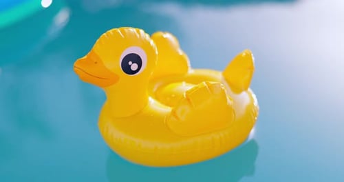 Aufblasbare gelbe Ente schwimmt an einem sonnigen Tag im Pool mit klarem blauem Wasser