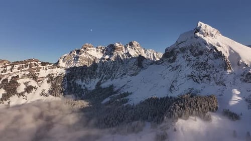 Fronalpstock snowy mountains and cloud layer aerial view – scenic Swiss alps in winter